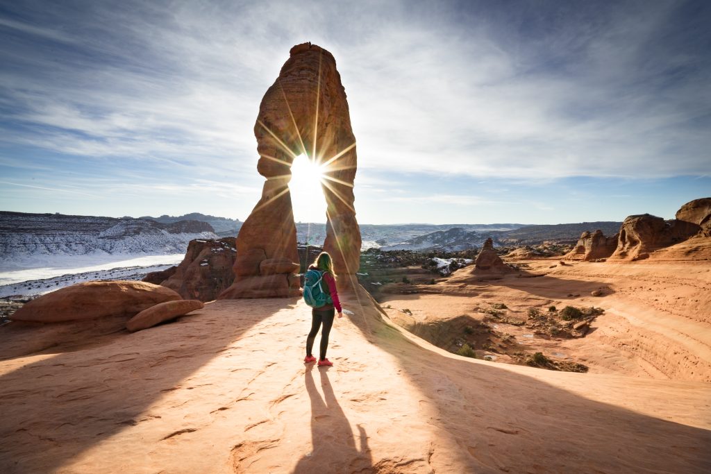 rear-view-woman-standing-by-rock-against-sky
